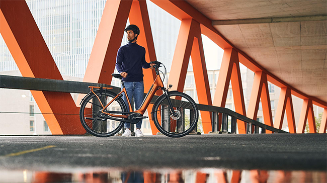 Mand står med hans giant elcykel under cykelbro